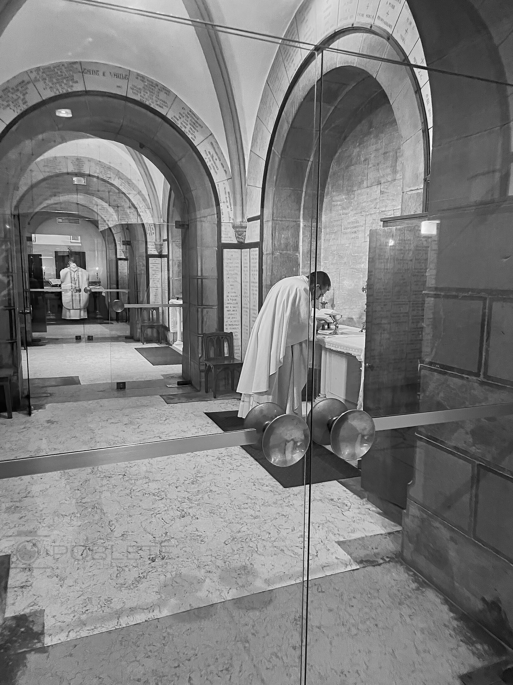 A solitary person kneels in a vaulted church nave.