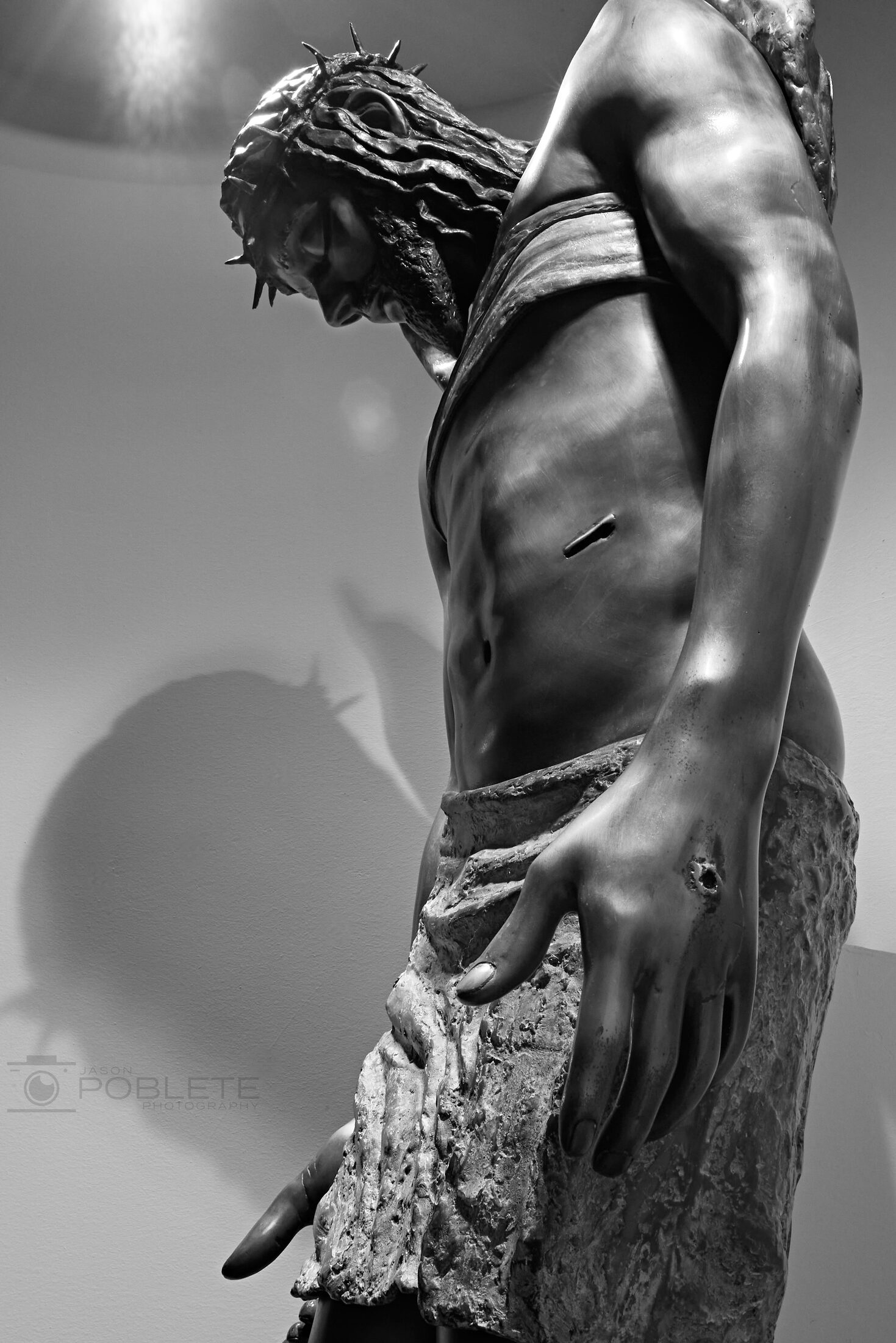 A close view of a weathered statue with raised arms.