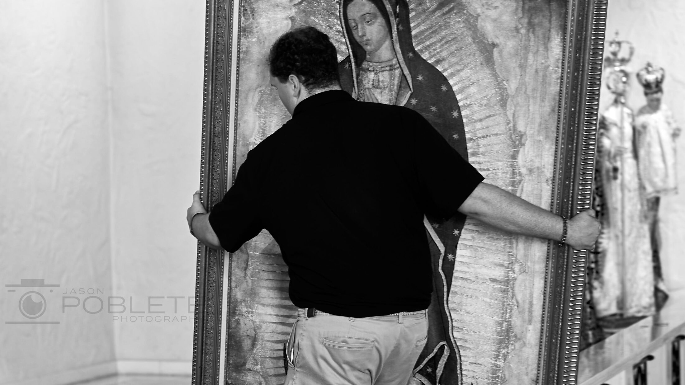 A man touches the surface of a large religious painting.