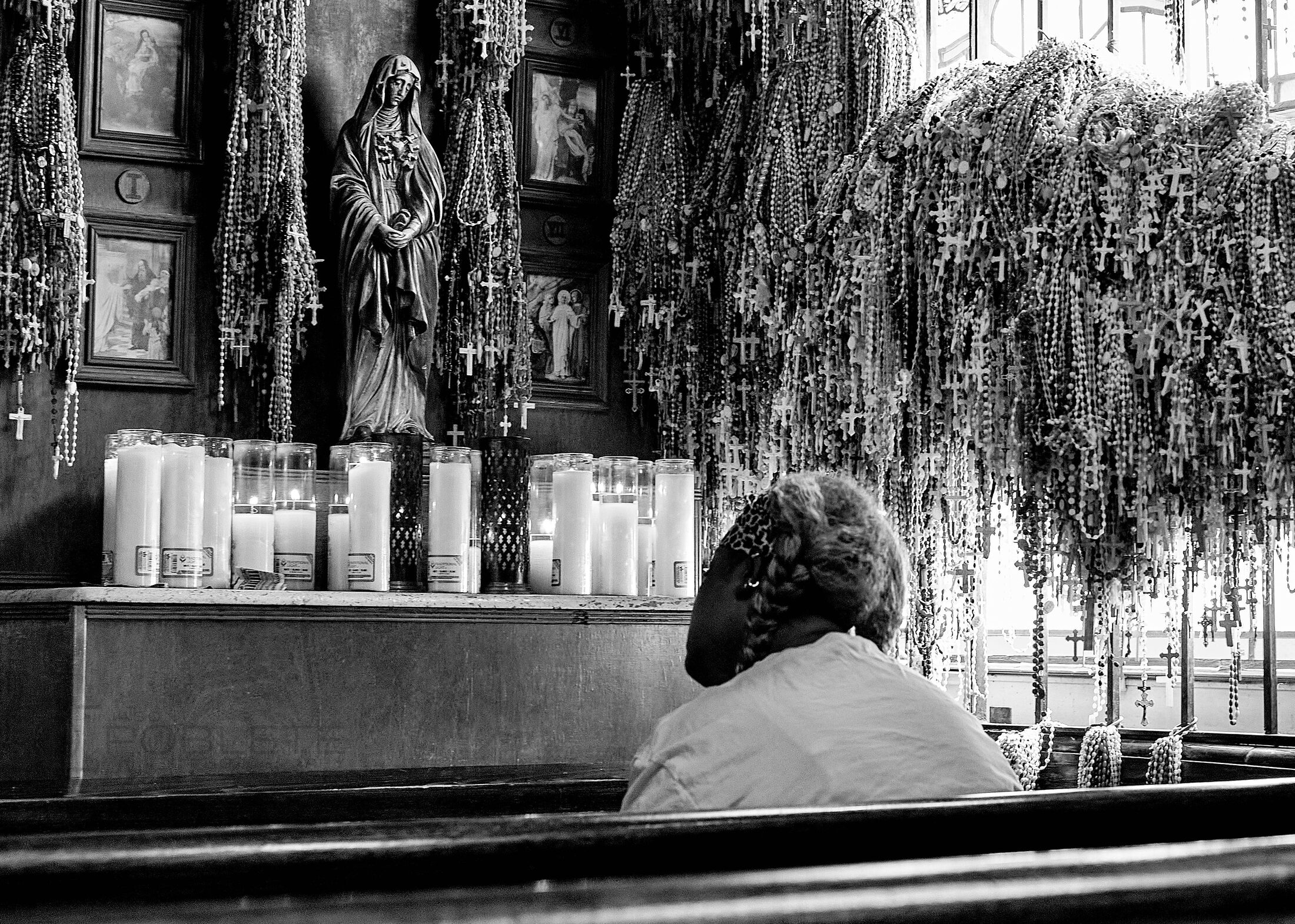 A person pauses before rows of devotional candles.
