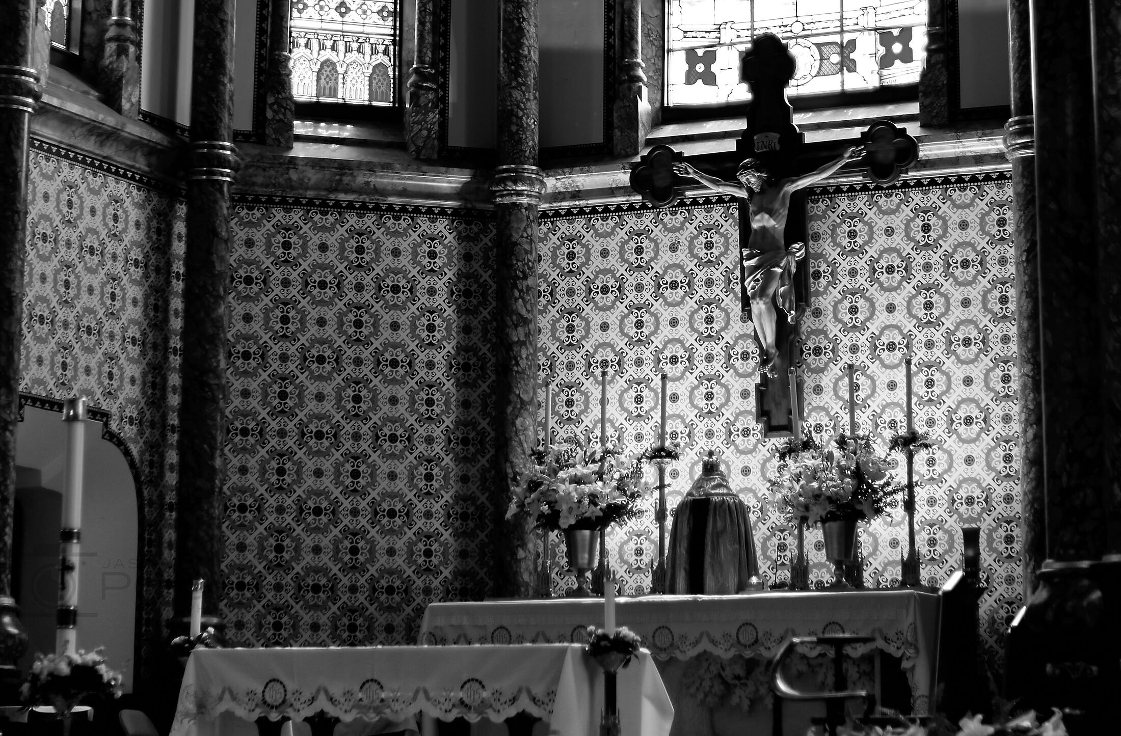 A worshipper kneels before an ornate altar in a dark church.