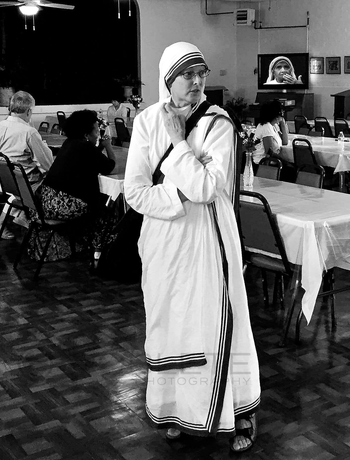 A nun speaks into a microphone at a public gathering.