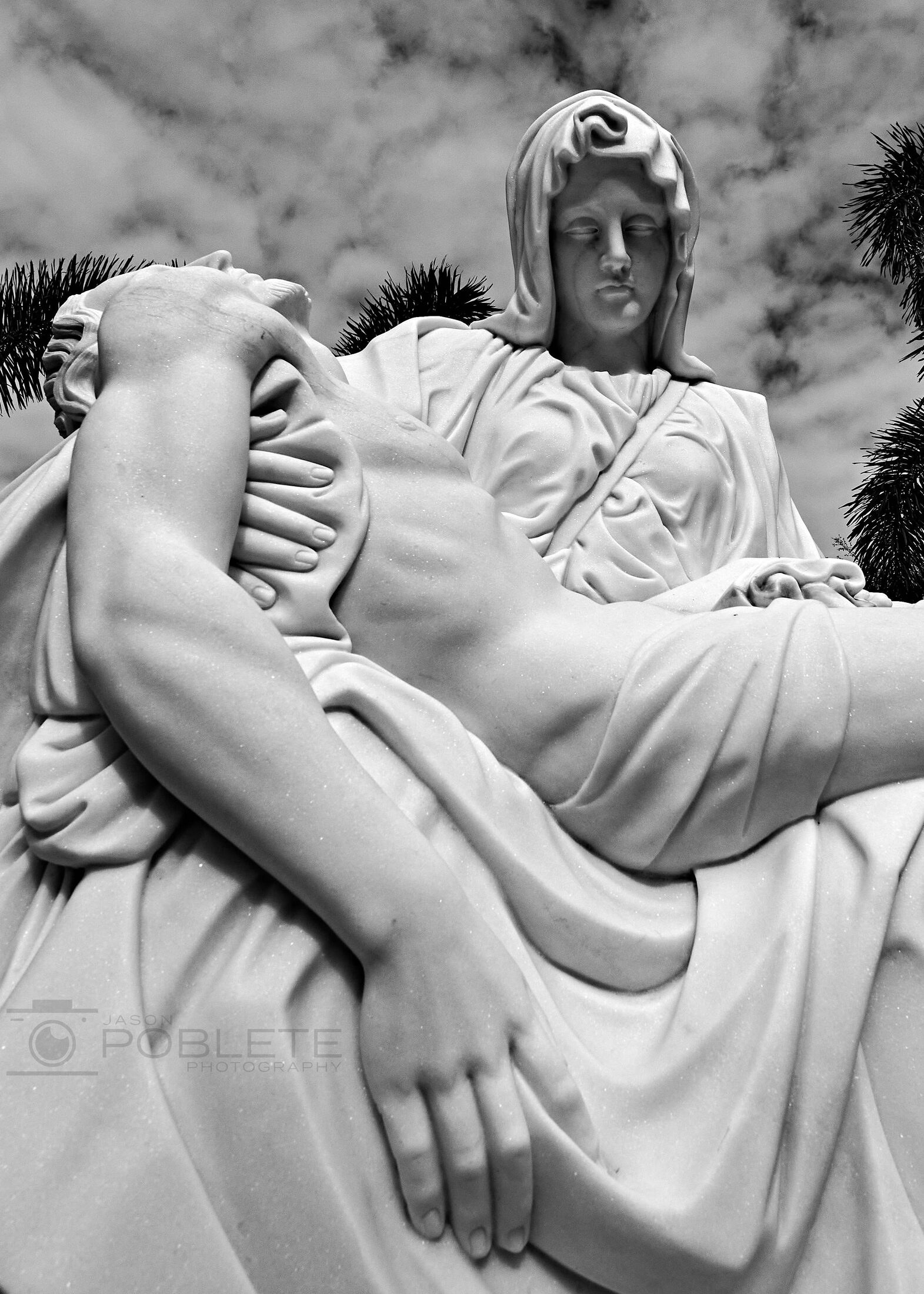 A stone sculpture shows a figure supporting a reclining body.