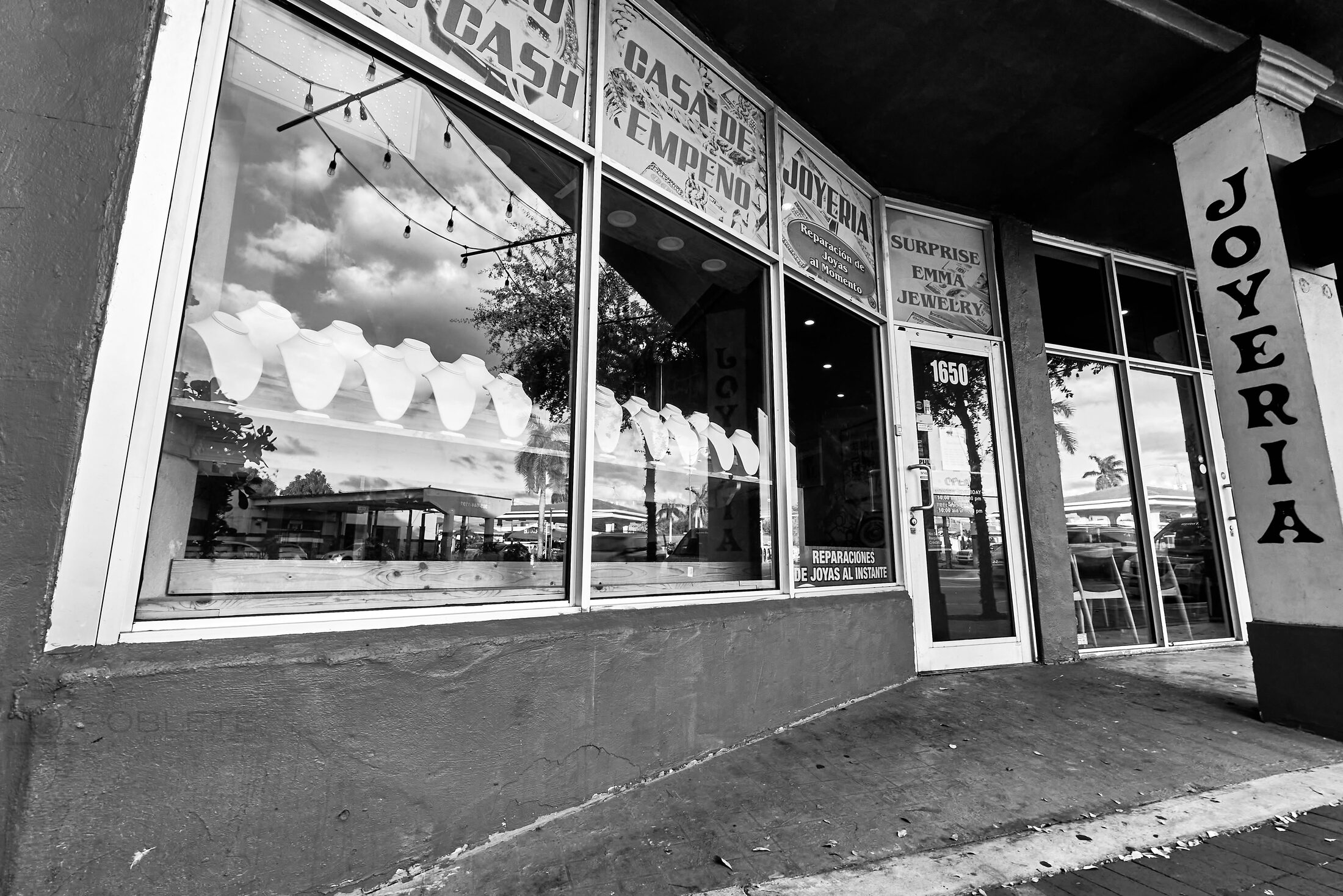Reflections fill the window of a small storefront on a quiet street.