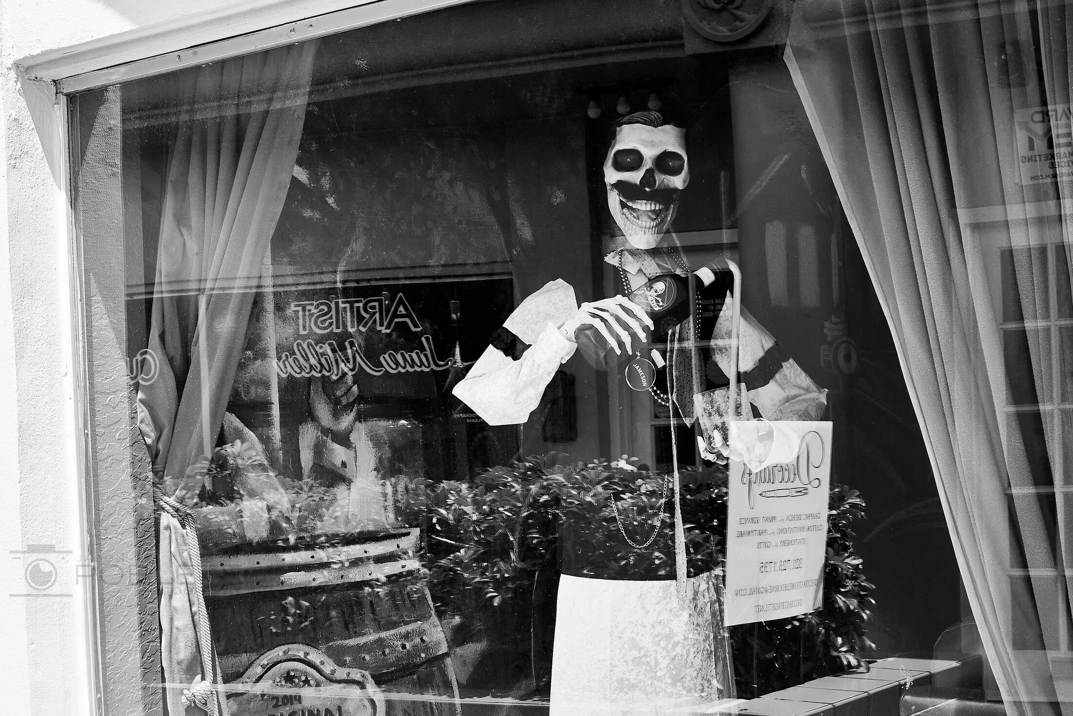 A costumed shopkeeper gestures from the doorway of a small store.