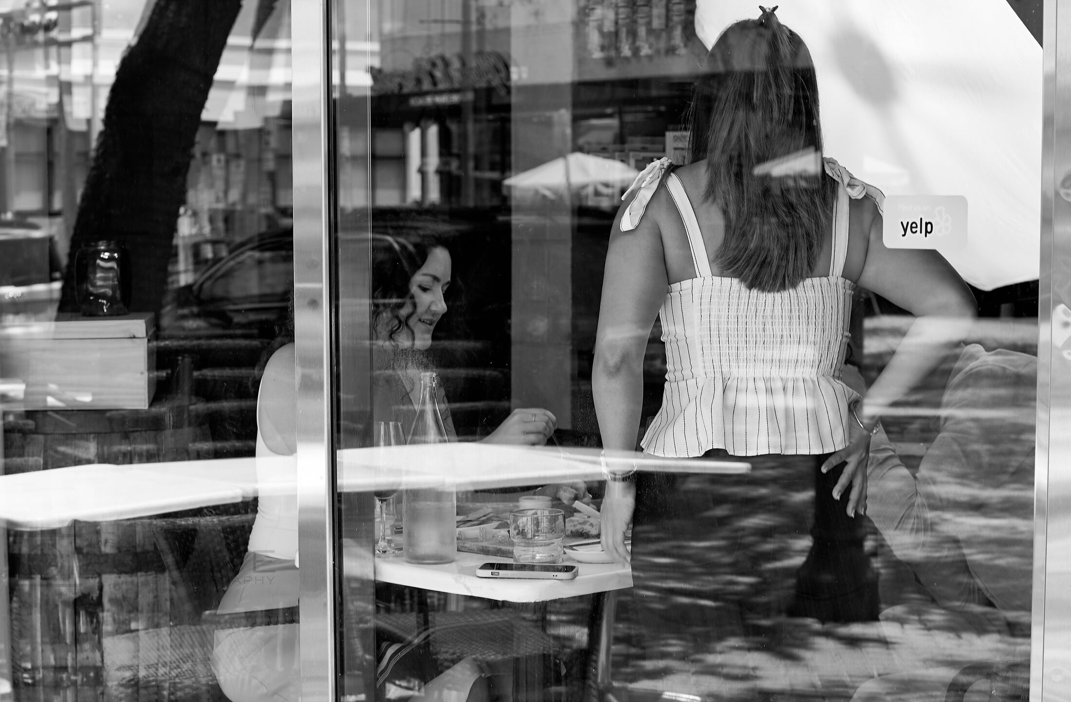 A shop employee is seen through layered window reflections.