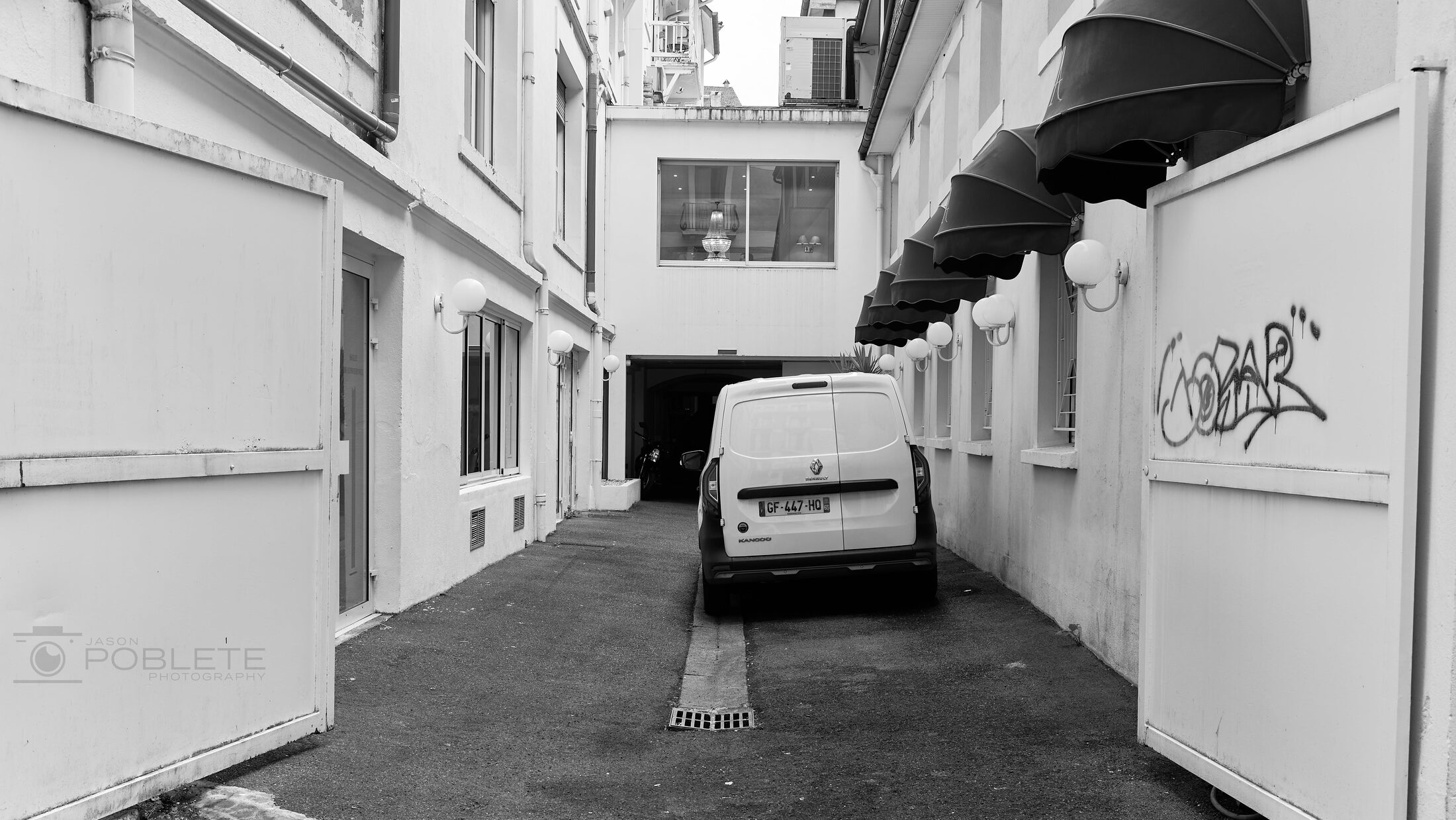A work van is parked in a narrow service lane.