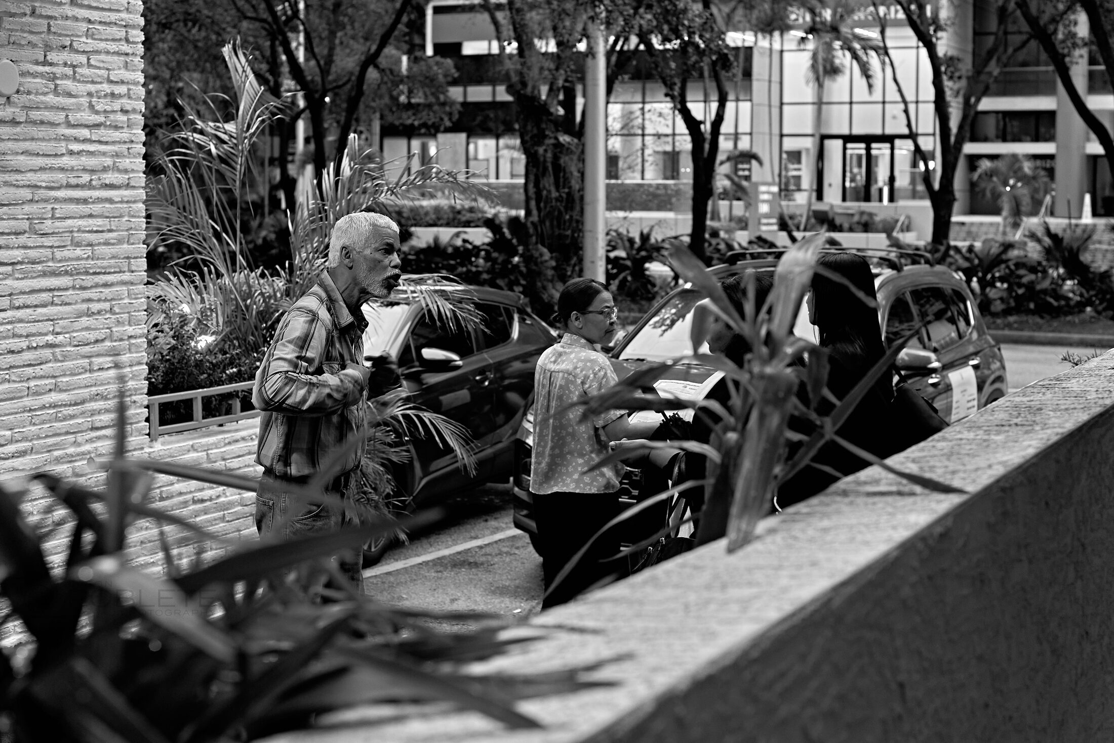 People sit along a crowded outdoor market stall.