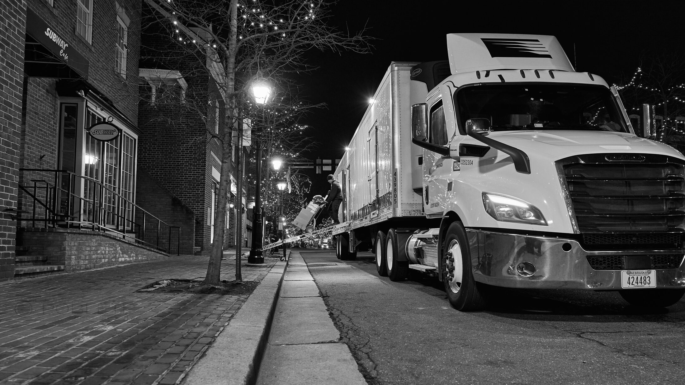 A vintage car is parked along a narrow street at night.