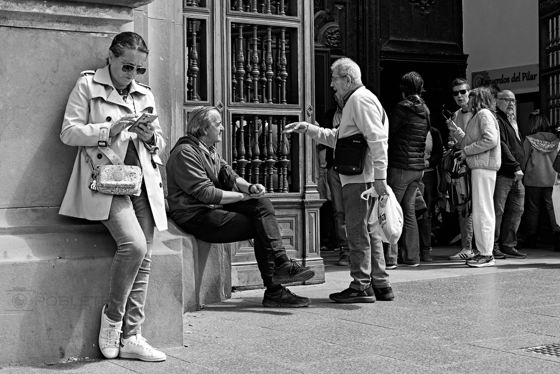 Three people sit and talk outside a storefront.