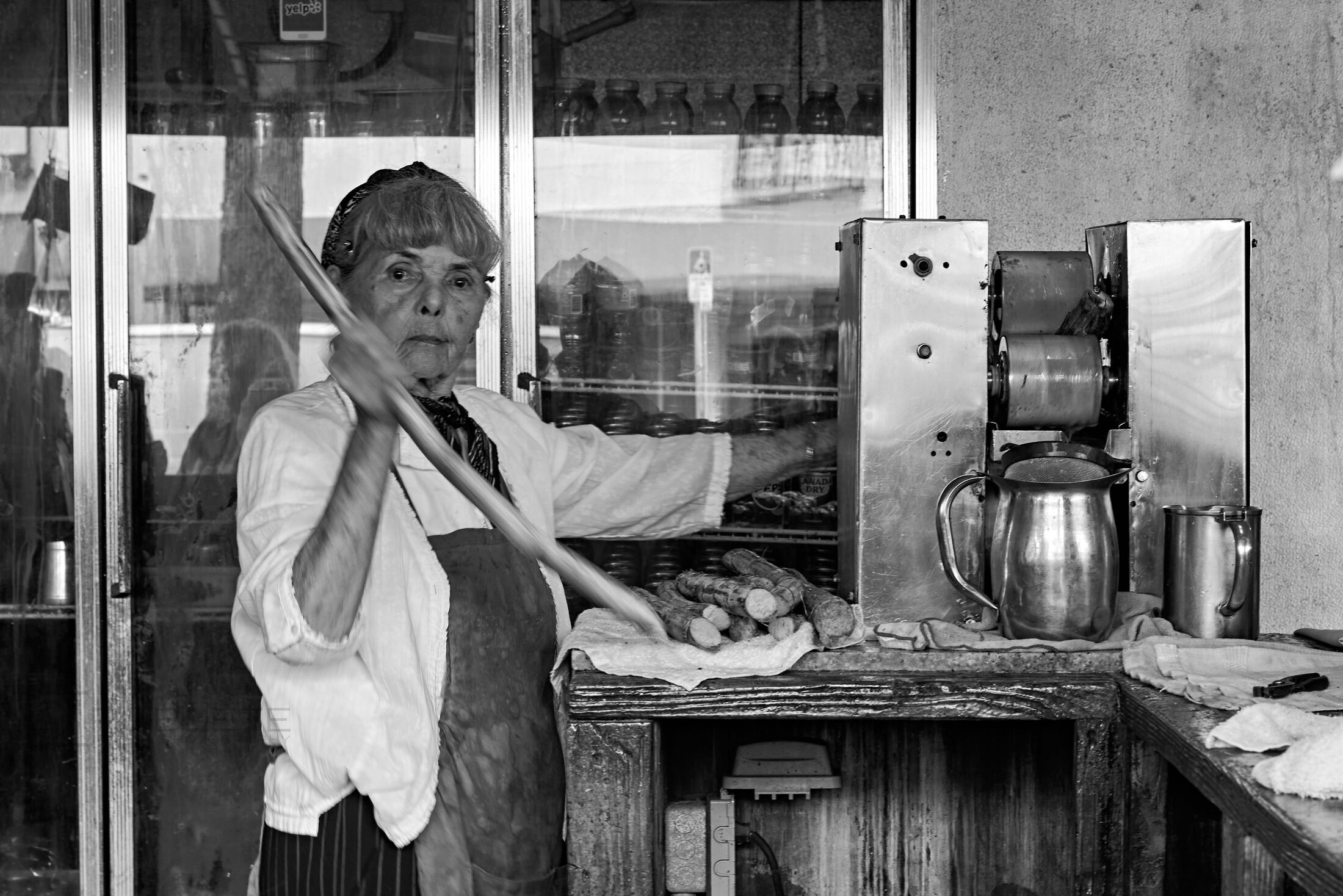 A person stands inside a small shop crowded with household objects.