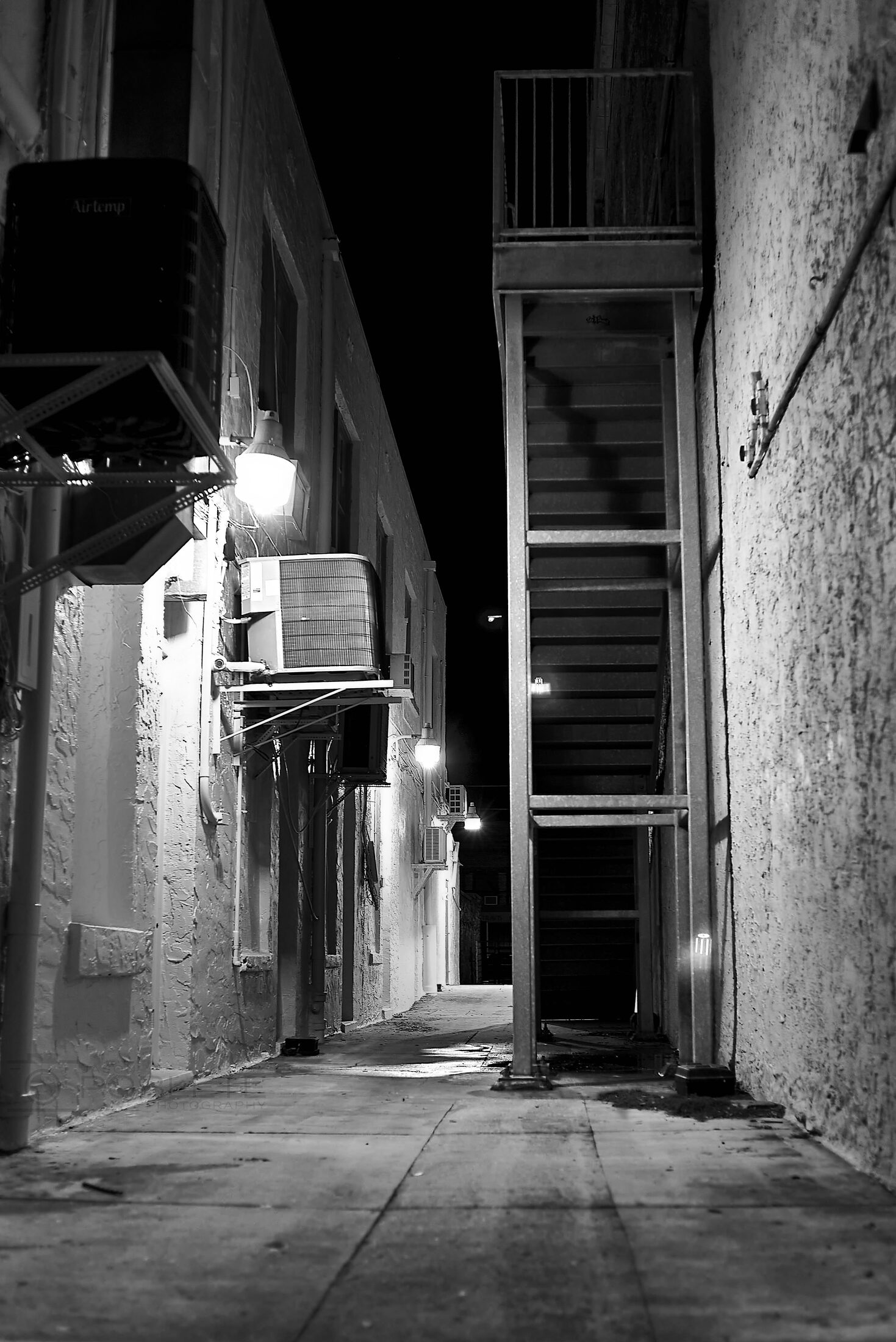 A narrow alley and doorway glow beneath a single lamp.