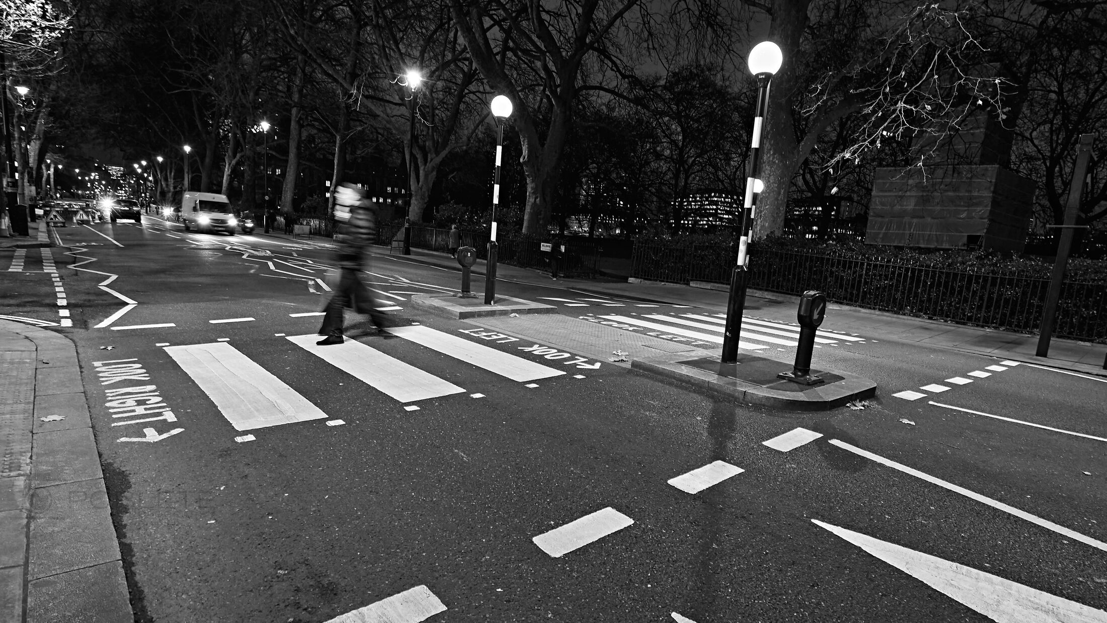 Bold crosswalk lines cut across an empty intersection at night.