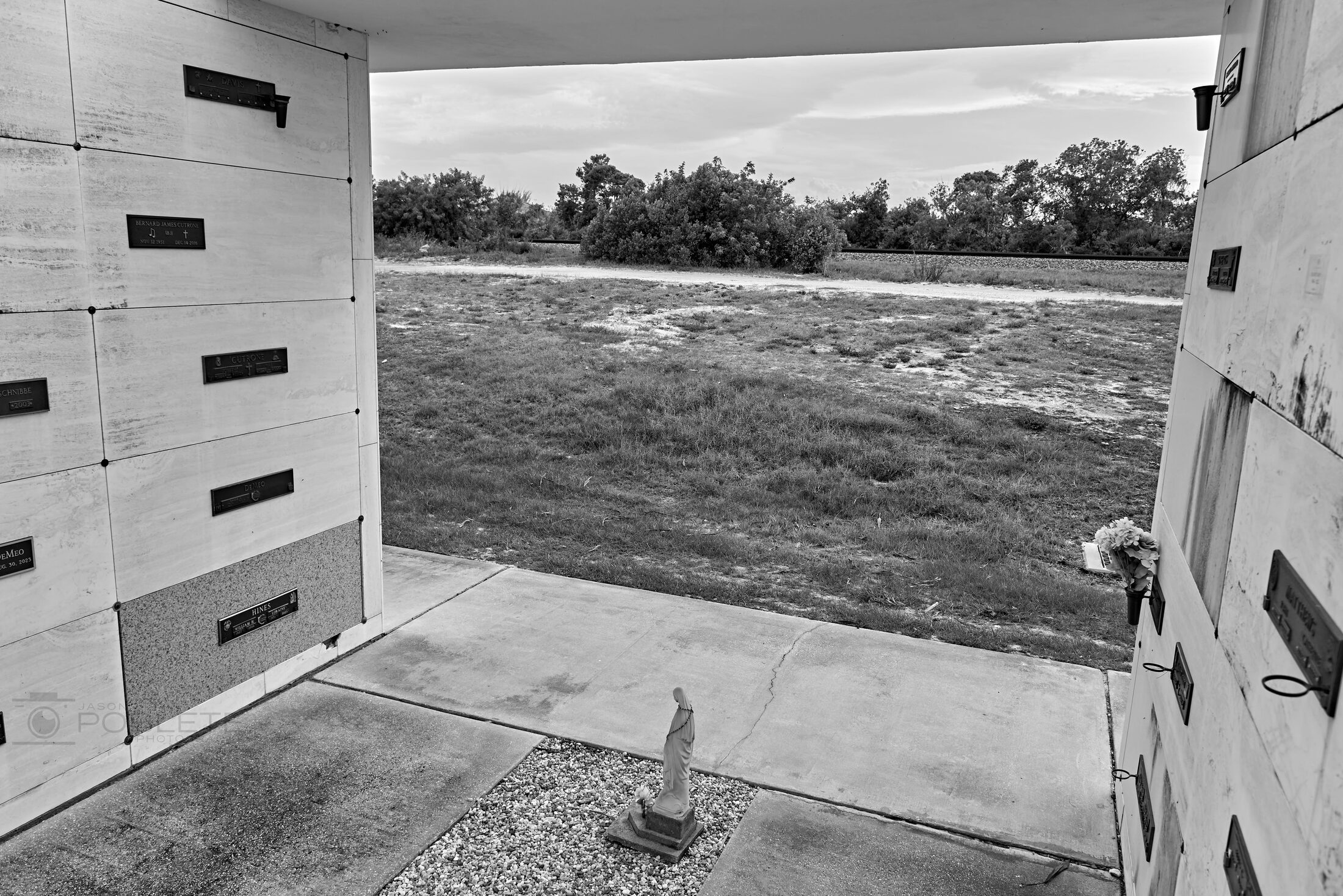 A cemetery lawn is viewed from inside an open mausoleum.