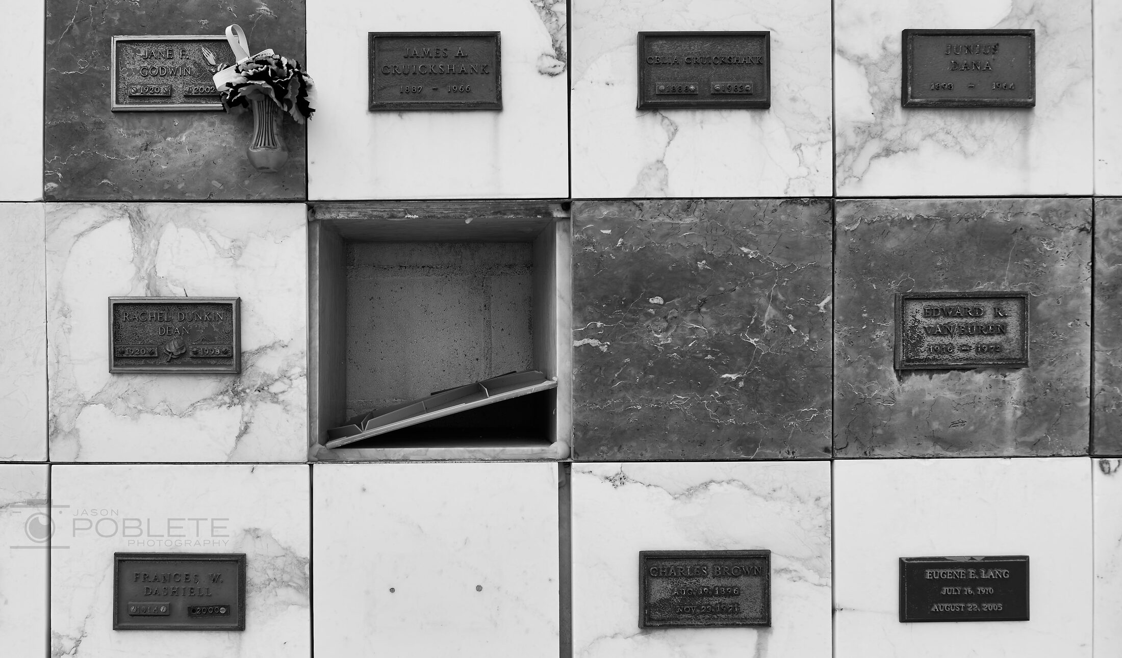 A grid of burial niches includes one open, dark compartment.