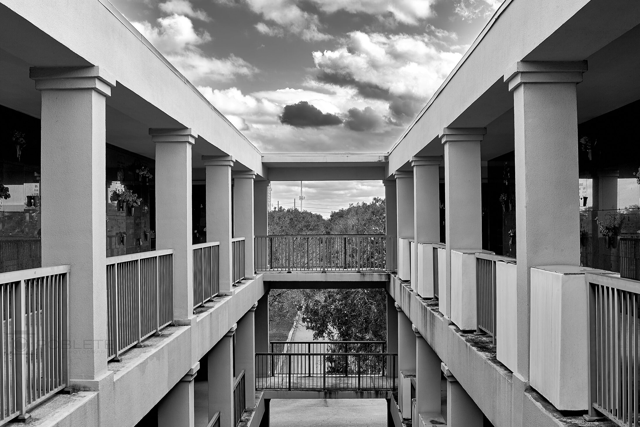 An open-air mausoleum corridor frames a dramatic cloudy sky.