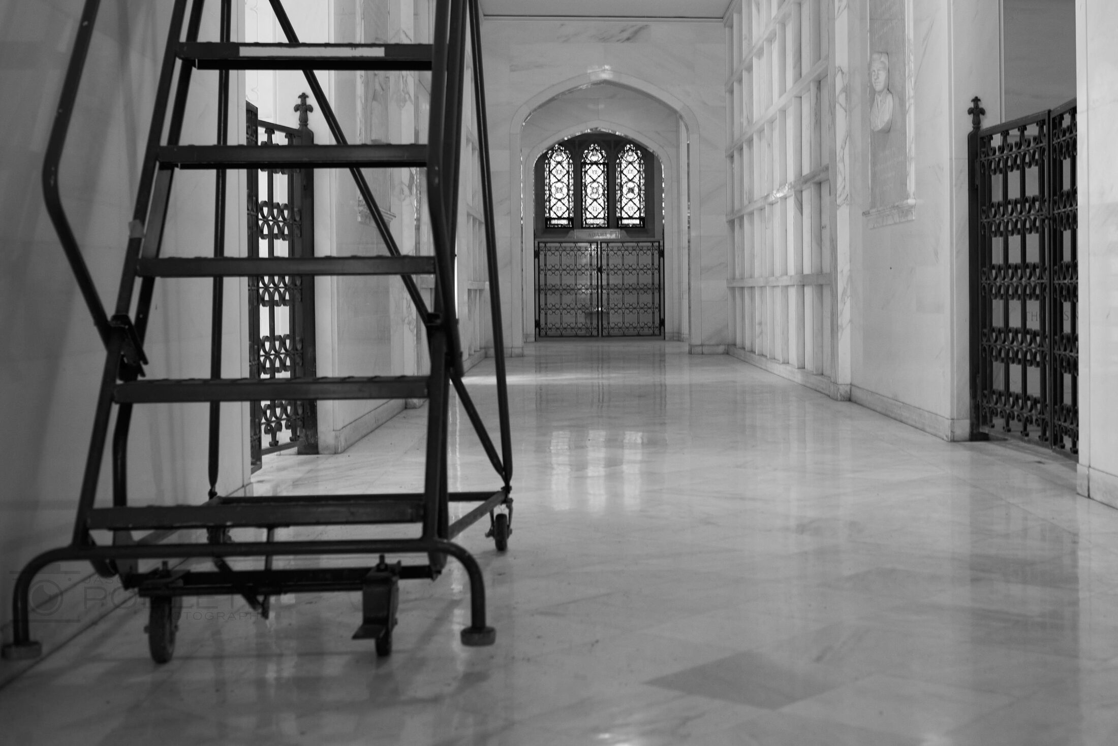 A ladder stands in an empty hall lined with burial niches.