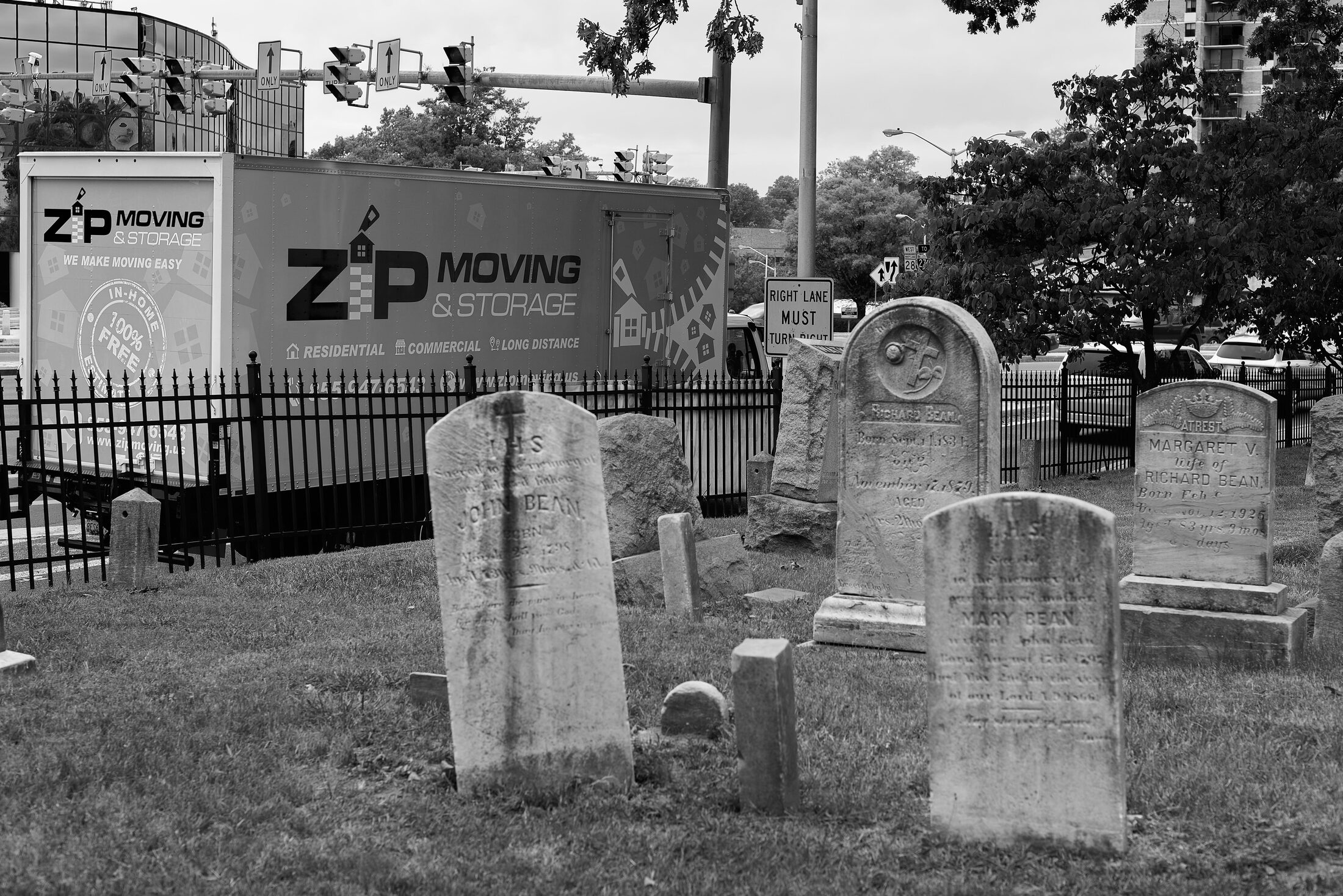 Headstones stand before a truck marked with cemetery equipment signage.