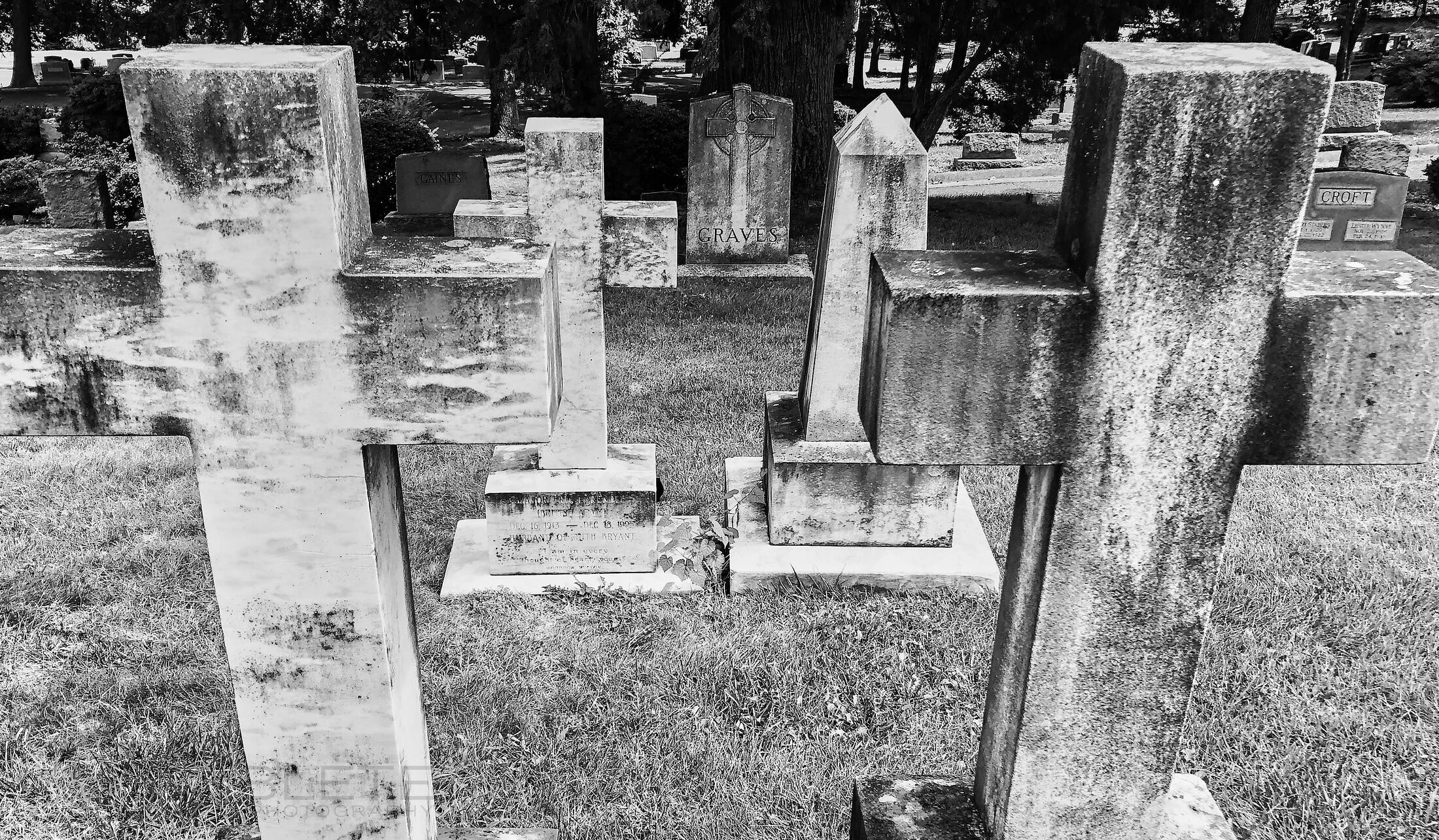 Two large stone crosses frame rows of weathered grave markers in a cemetery.