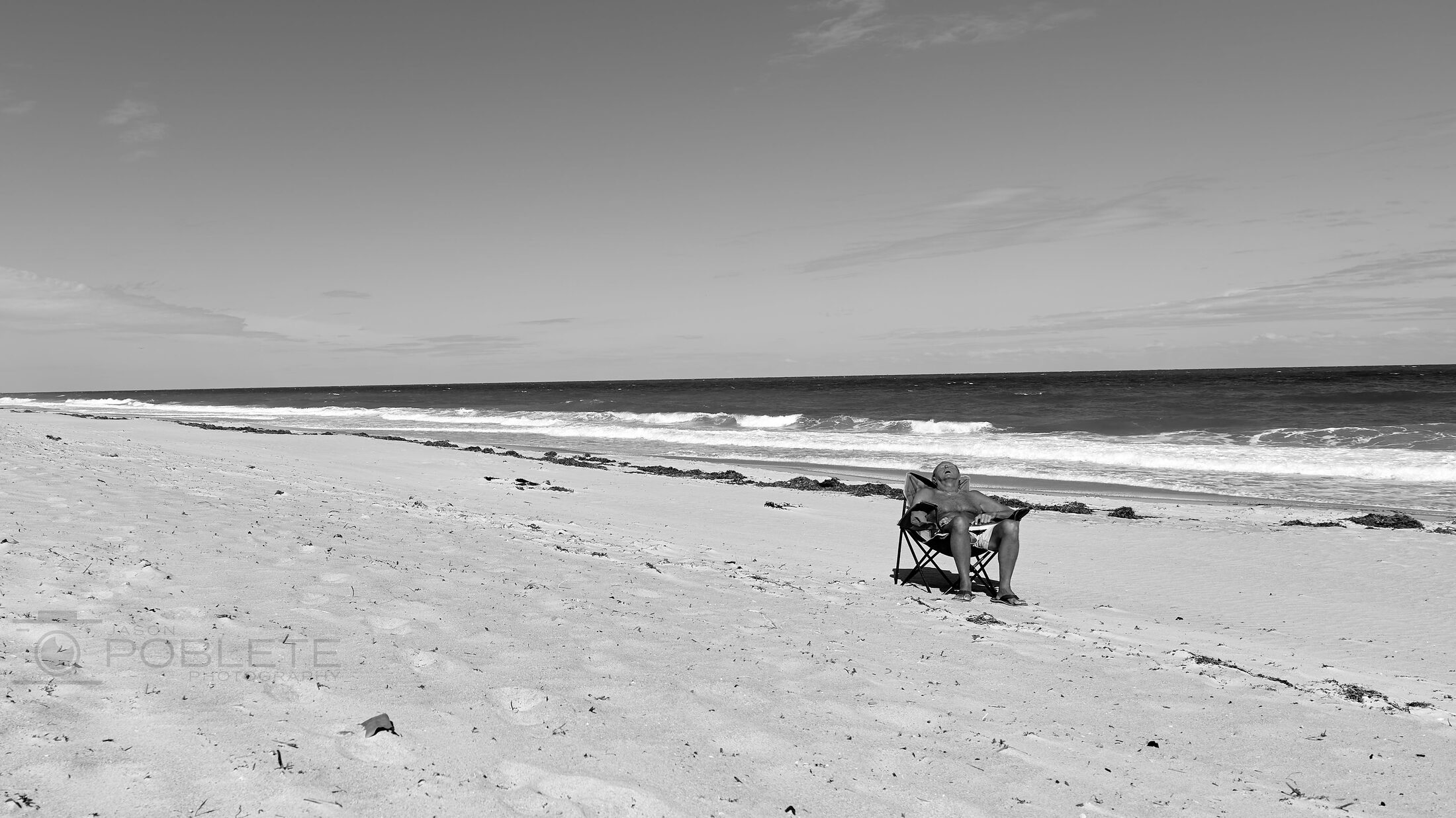 A small utility vehicle travels along a nearly empty beach.